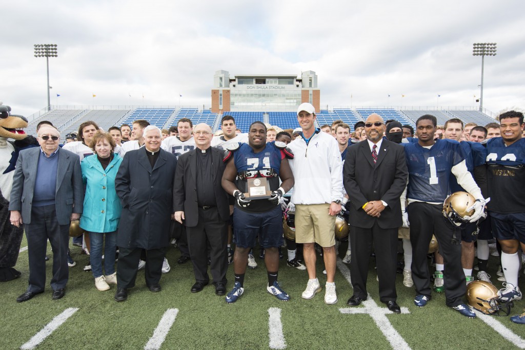 John Carroll University Defensive Lineman David Porter, center, receives the Allstate AFCA "Good Works Team" trophy (Oct. 29, 2015). Photography: Alex Slitz
