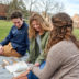 Three students sit on a blanket on the Hamlin Quad and study