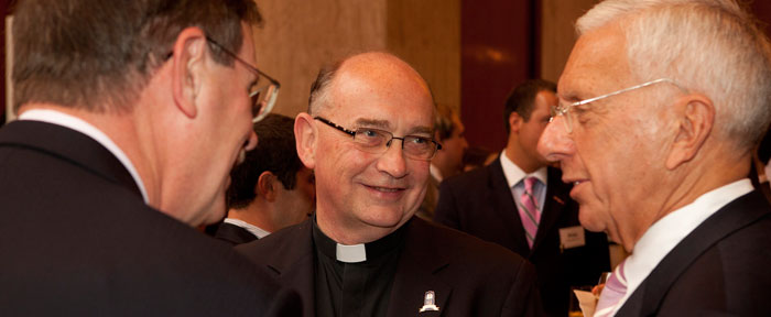Priest smiling and talking to faculty